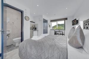 a white bedroom with a large bed and a bathroom at Captivating 1-Bed Studio in Feltham in Feltham
