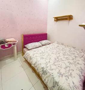 una piccola camera con letto con testiera viola di Homestay KP a Kepala Batas