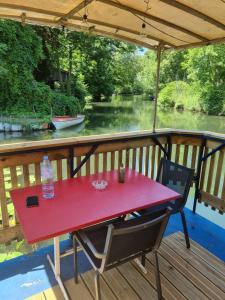 een rode tafel op een terras met uitzicht op een rivier bij Au fils de l'eau in Straatsburg