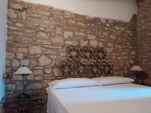 1 dormitorio con pared de piedra, 1 cama y 2 lámparas en Villa Luisa, en Ziano Piacentino
