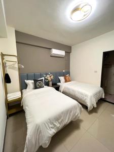 2 Betten in einem Zimmer mit weißer Bettwäsche in der Unterkunft Haoyue Hotel in Jincheng