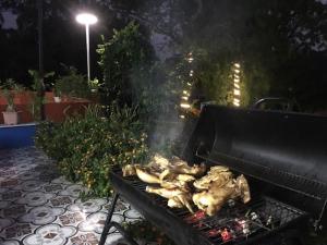 a chicken cooking on a grill in a backyard at night at Catba Papillon Garden Bungalows & Resort in Cat Ba
