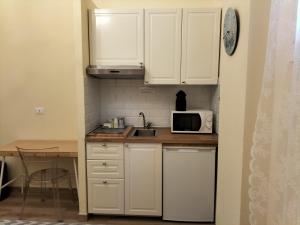 a small kitchen with white cabinets and a microwave at BolognaFiera in Bologna