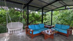 a porch with blue couches and a swing at Four Trees Jungle Lodge in San Juan del Sur
