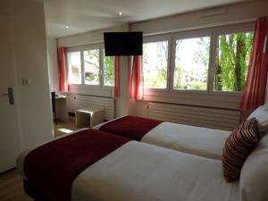 a hotel room with two beds and two windows at Cit'Hotel Escatel in Mâcon
