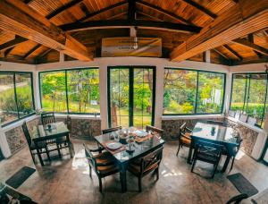 un comedor con mesas, sillas y ventanas en Hill Safari - Tea Estate Villa en Ohiya