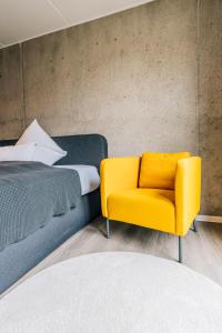 Urban City Lifestyle Appartement في بيليفيلد: غرفة نوم وكرسي اصفر بجانب سرير