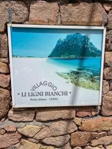 un cartello su un muro di mattoni con la foto di un'isola di DomoMea - Le Ginestre a Porto Istana