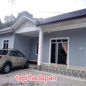 a house with a car parked in front of it at Raptronics Homestay Kampung in Kota Bharu
