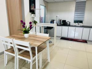 a kitchen with a wooden table and chairs with purple flowers at VTH Homestay Drawbridge Ladang Tanjung, Kuala Terengganu with POOL, Drawbridge, KTCC Mall, Pasar Payang in Kuala Terengganu +5 photos