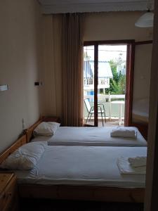 two beds in a bedroom with a view of a balcony at PANAGIOTIS in Pefki