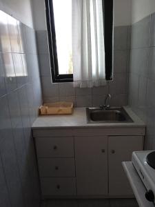 uma pequena cozinha com um lavatório e uma janela em PANAGIOTIS em Pefki