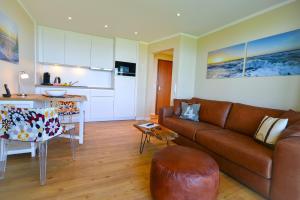 a living room with a brown couch and a kitchen at Haus Horizont H511 in Cuxhaven