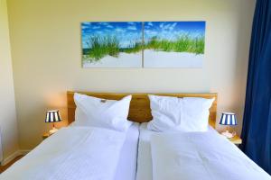 2 Betten mit weißen Kissen in einem Schlafzimmer mit 2 Lampen in der Unterkunft Haus Horizont H511 in Cuxhaven