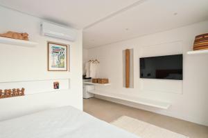 a bedroom with white walls and a tv on the wall at Auka Boipeba in Ilha de Boipeba
