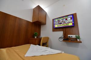 a bedroom with a bed and a tv on the wall at Hotel Surya Lodge in Mysore