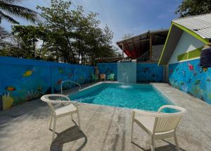 a swimming pool with two chairs in front of a blue wall at Hotel El Icaco Tortuguero in Tortuguero