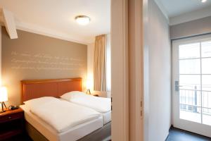 ein Hotelzimmer mit einem Bett und einem Fenster in der Unterkunft Batschari Palais Baden-Baden in Baden-Baden