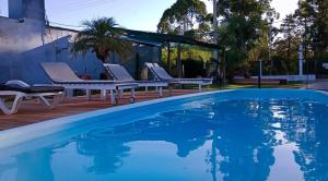 a swimming pool with two lounge chairs next to a house at Bungalows La Pilarica in Federación