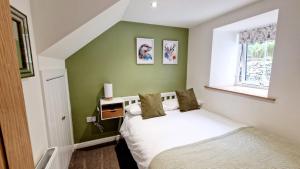 a bedroom with a white bed and a green wall at Nordlys Cottage in Newton Stewart