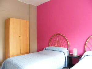 - une chambre avec 2 lits et un mur rose dans l'établissement Pensión Corona, à Saragosse