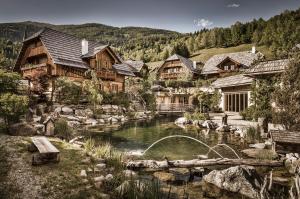 a house with a pond in front of a mountain at st martin chalets in Sankt Michael im Lungau