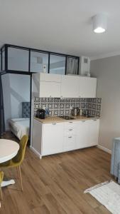 uma cozinha com armários brancos e uma mesa num quarto em Apartament na Starówce em Elblag
