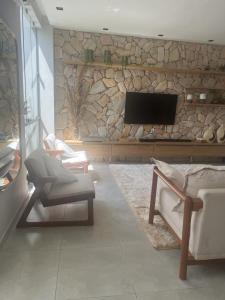 a living room with a stone wall with a tv at Casa por temporada in Santarém