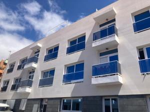 a white building with blue windows and a sky at Casa Brillante in Playa de San Juan
