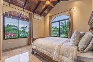 a bedroom with a bed and two large windows at Las Palomas Villas Of Uvita in Uvita