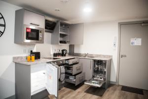 une cuisine avec des placards gris et des appareils blancs dans l'établissement Luxurious City Center 1 BR Vibrant Liverpool, à Liverpool