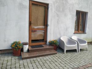 a patio with two white chairs and a door at Svitiaz Griada in Szack
