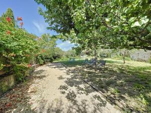 a dirt road with two chairs under a tree at LA BOULANGERIE in Saint-Sauveur-de-Cruzières