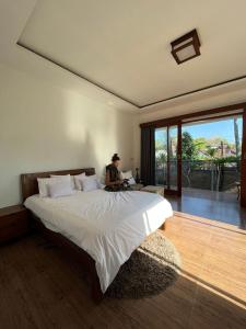 a person sitting on a bed in a bedroom at The luxe villas lombok in Kuta Lombok