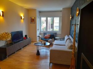 a living room with a couch and a tv at Grd maison 6 Couchages, 25 mn du stade en métro in Lambersart