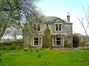 uma antiga casa de tijolos com um quintal verde em Traditional Family Stone Farmhouse, sleeps 12, St Andrews em St. Andrews