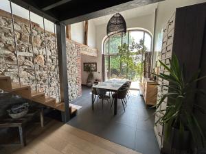 uma sala de jantar com uma mesa e uma parede de pedra em La villa du Tilleul em Stoumont