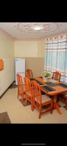 een keuken met een tafel en stoelen en een koelkast bij Makindye Kizungu Holiday Villa in Makindye
