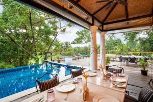 a dining area with a table and chairs and a swimming pool at Sol De Goa in Nerul
