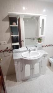 La salle de bains blanche est pourvue d'un lavabo et d'un miroir. dans l'établissement Val do Fragoso, à Vigo