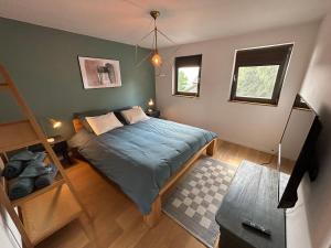 ストゥモンにあるLa villa du Tilleulのベッドルーム1室(青い掛け布団、窓2つ付)