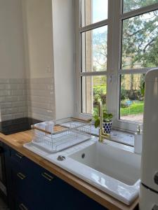 La salle de bains est pourvue d'un lavabo et d'une fenêtre. dans l'établissement Bright Apt 70m2 in Bayeux historic center w Pkg, à Bayeux