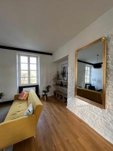 een woonkamer met een bank en een spiegel bij Bright Apt 70m2 in Bayeux historic center w Pkg in Bayeux