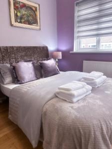 a purple bedroom with two beds with towels on them at Cosy apartment in London