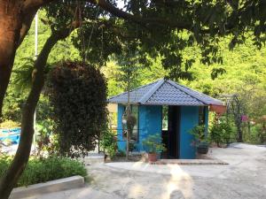 a blue building in a garden with a tree at Catba Papillon Garden Bungalows & Resort in Cat Ba