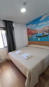 una camera da letto con un letto e un dipinto sul muro di Hostal Zaragoza Centro a Saragozza