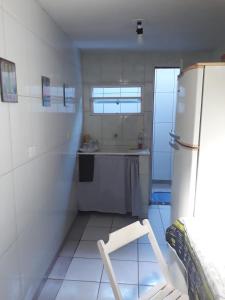 eine kleine Küche mit einem Kühlschrank und einem Stuhl darin in der Unterkunft Chalés sal da terra/Chalé in Caraguatatuba