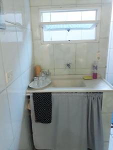 ein weißes Bad mit einem Waschbecken und einem Fenster in der Unterkunft Chalés sal da terra/Chalé in Caraguatatuba