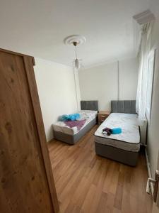 two beds in a small room with wooden floors at Çift klimalı, 110m2, 3+1, metro 5dk, 1000mbps inte in Karşıyaka