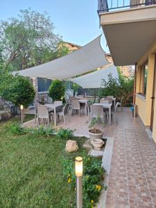 un patio con mesas y sillas bajo una sombrilla blanca en B&B Villa Chiara Bed and Breakfast en Taormina